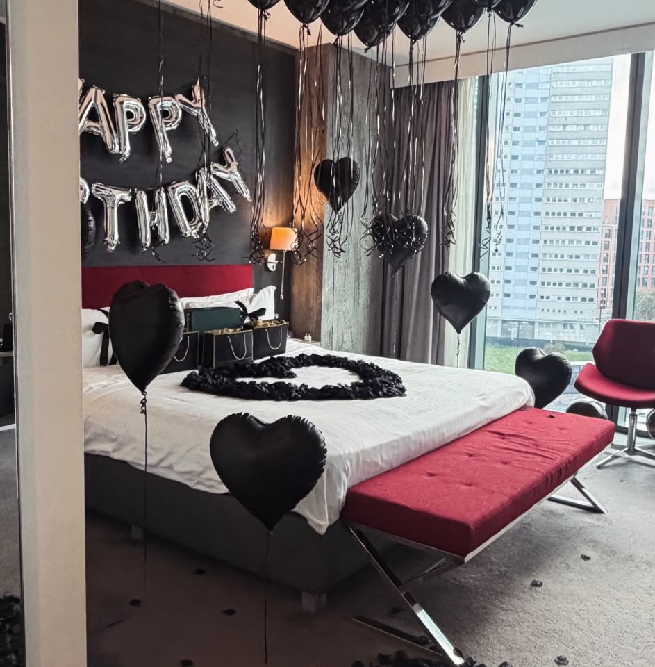 Black balloon birthday room with a heart-shaped balloon and black rose design on the bed