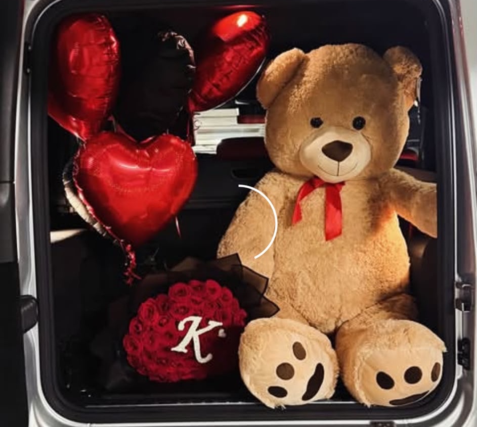 A birthday gift surprise with red heart balloons, roses and a teddy bear